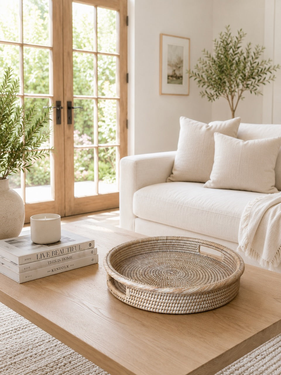 Alden rattan tray in a living room with a white sofa, wooden coffee table, and decorative items.