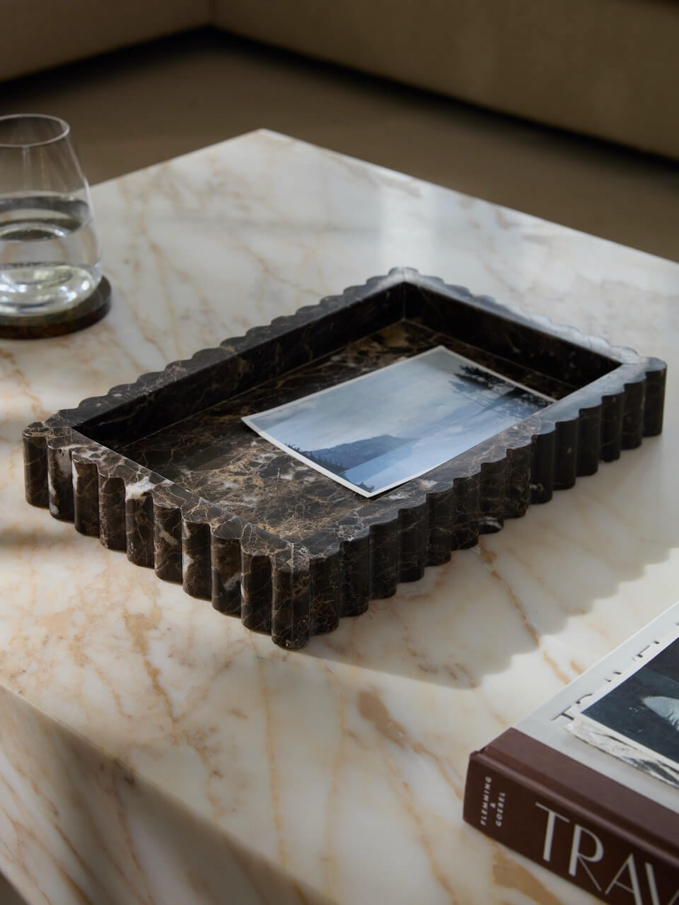 Decorative stone tray on a marble surface with a glass and book in the background