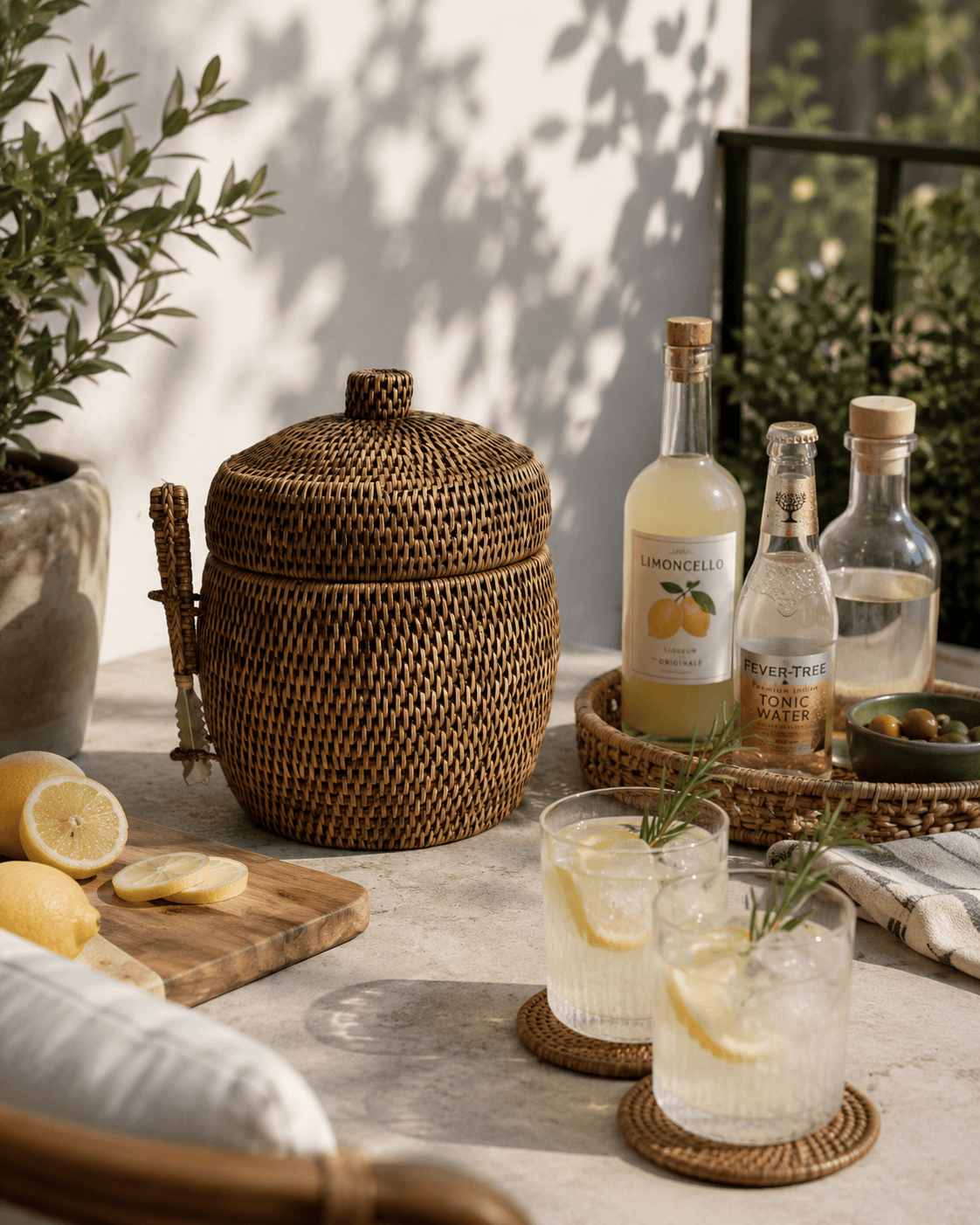 Outdoor setting with drinks, lemons, and a Minto rattan ice bucket on a table.