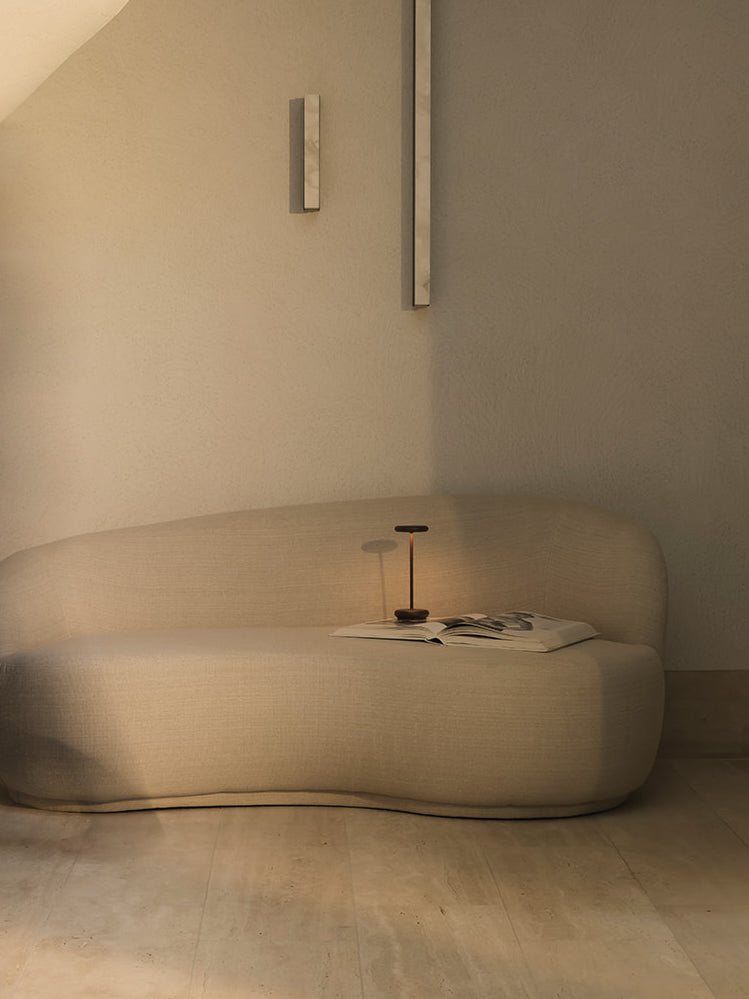 Lana cordless rechargeable table lamp in corten finish creating warm ambient light on sofa in neutral interior modern dimmable table lamp styling