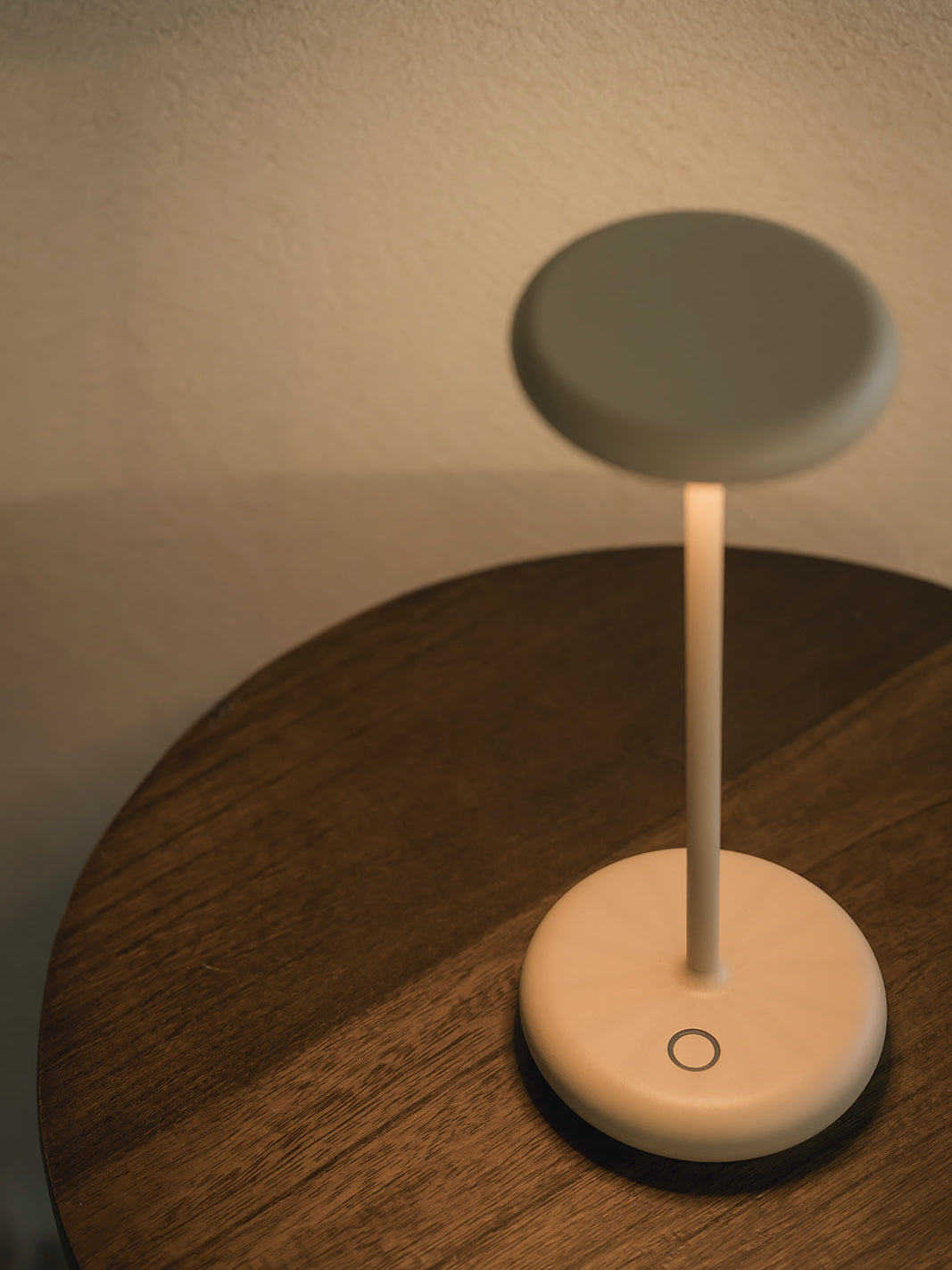 Lana rechargeable table lamp in sand finish close-up showing dimmable cordless design and warm ambient lighting on wooden side table