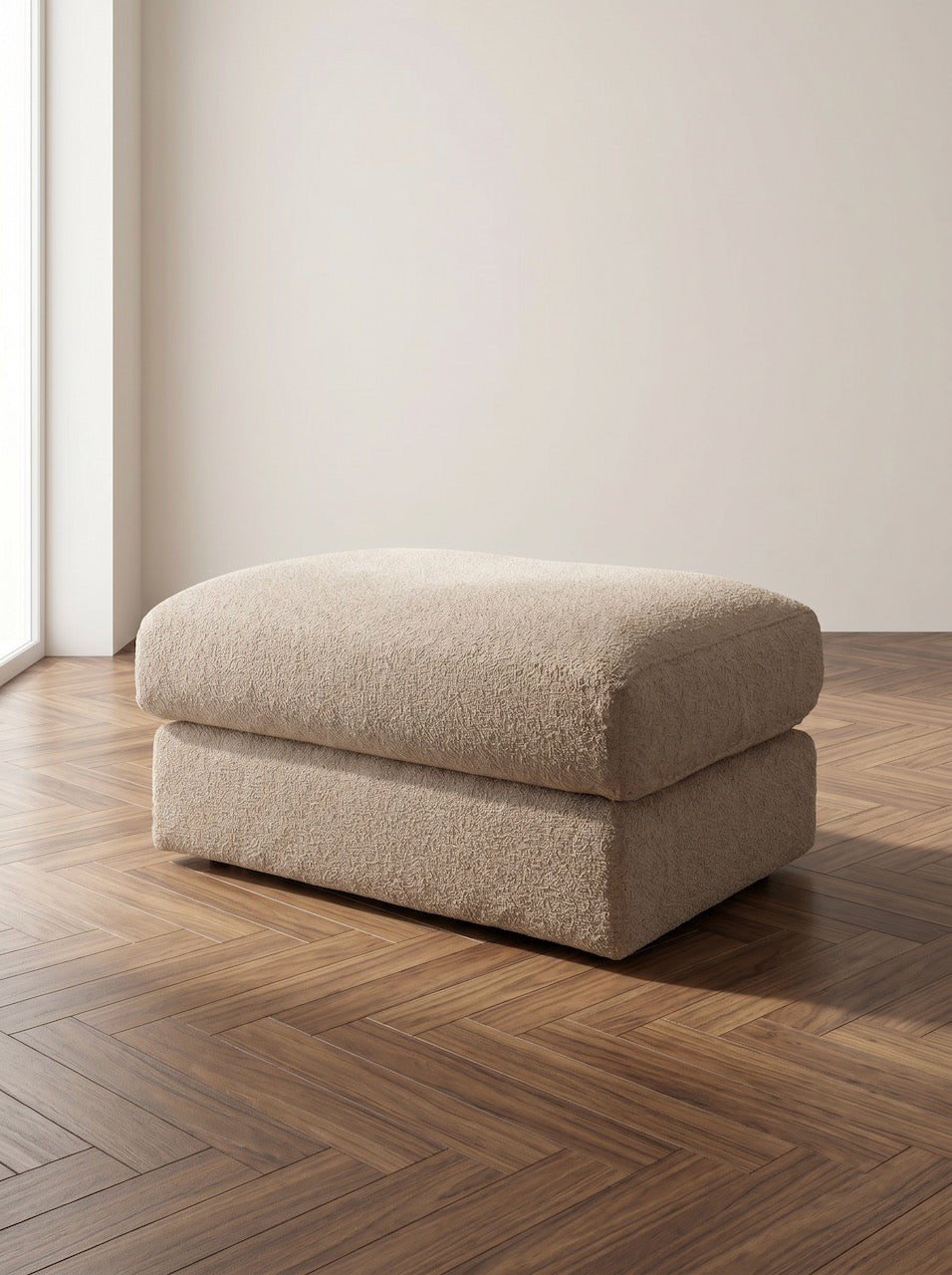 Beige ottoman on a wooden floor with a plain wall background