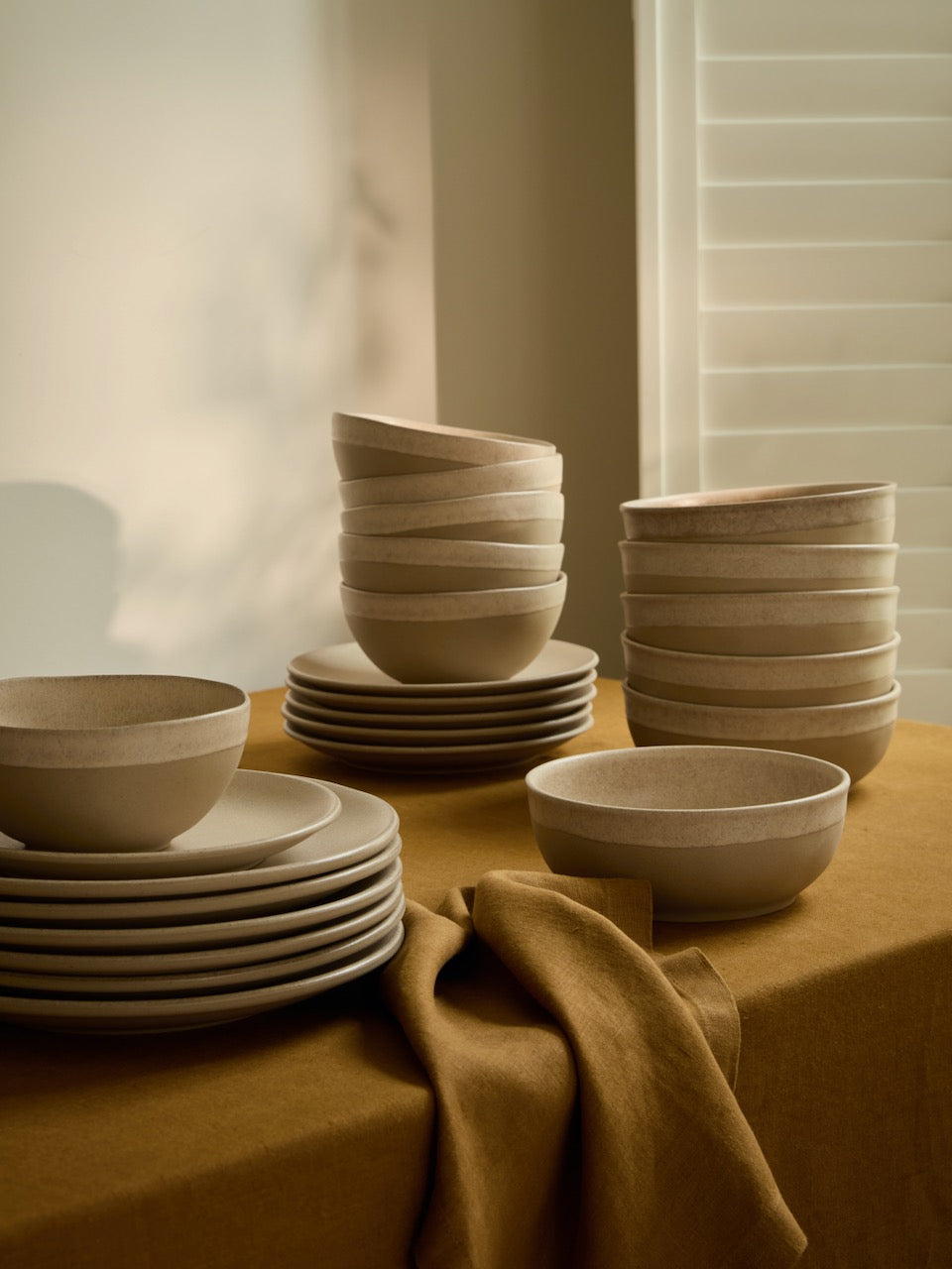 Arenito stoneware in warm sand and muted olive tones