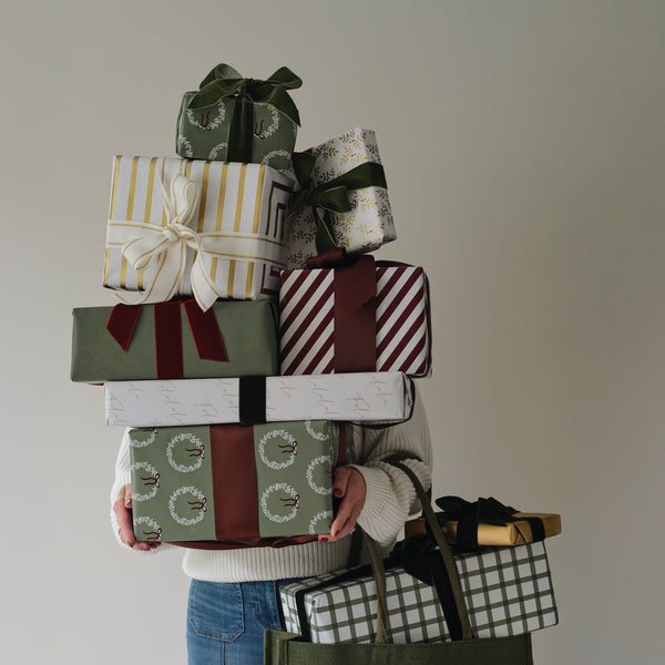 A stack of gifts wrapped in patterned paper and ribbon