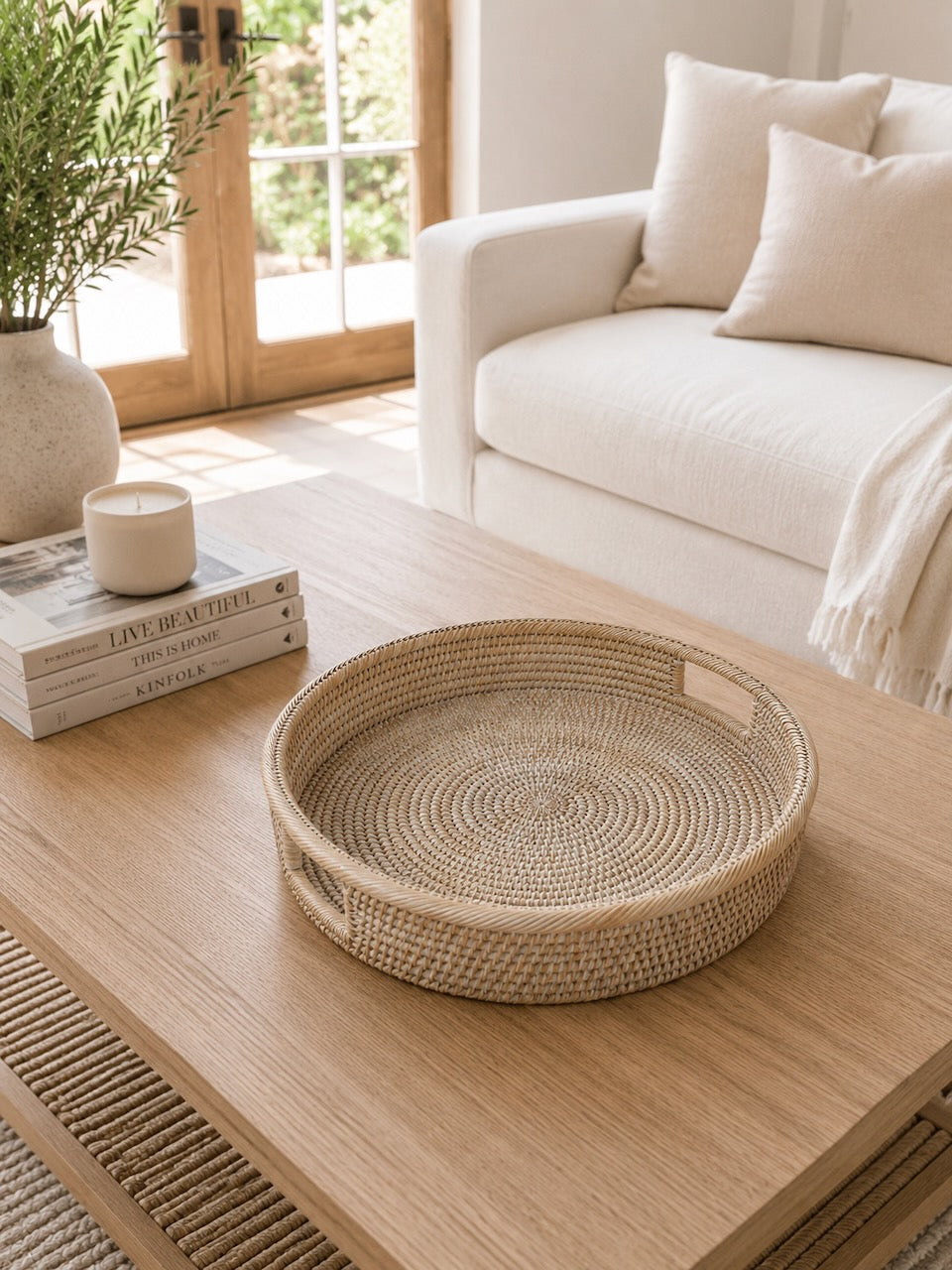 Alden rattan tray on a wooden coffee table in a living room with a couch and decor items.