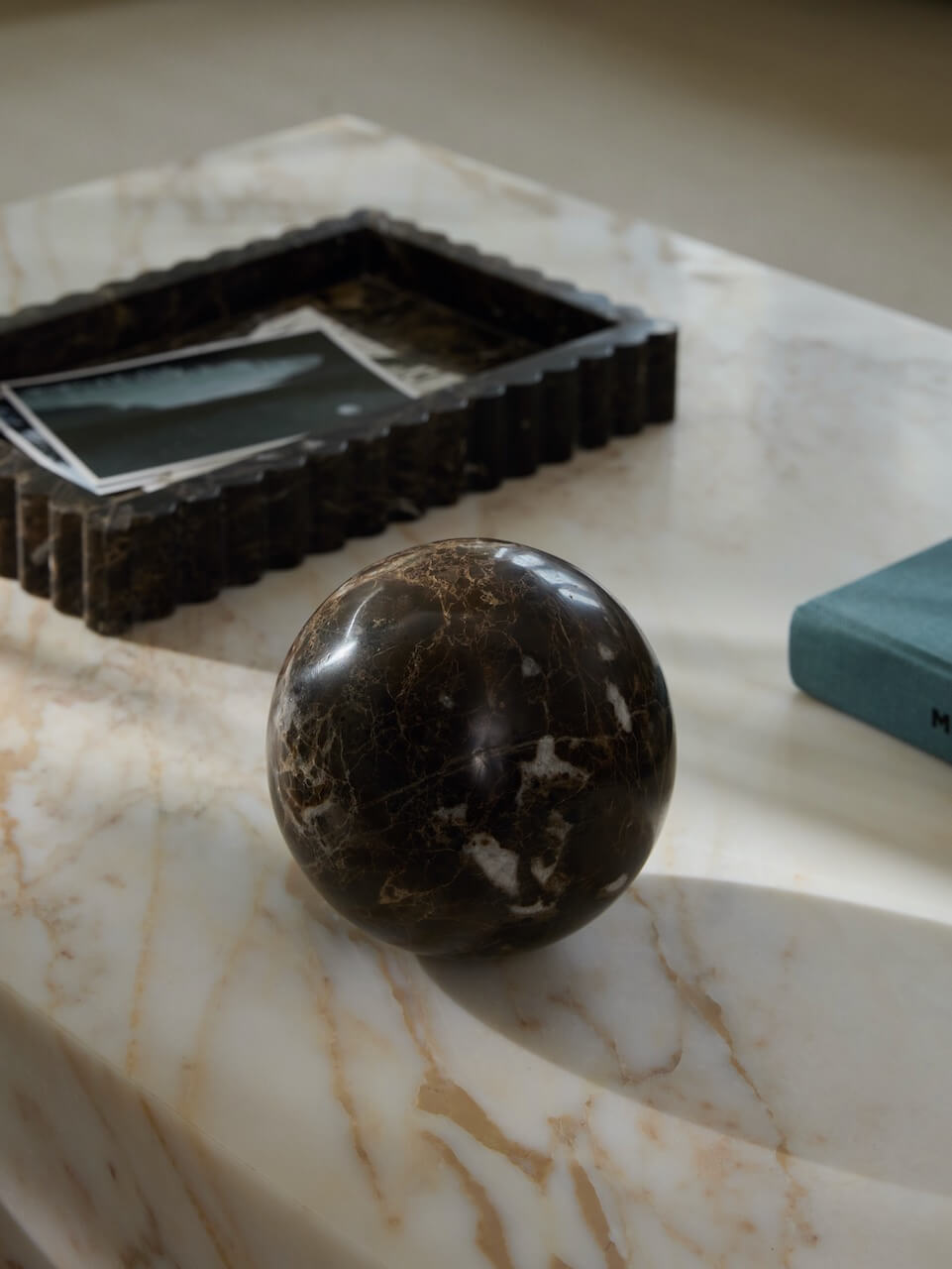 Marble surface with a dark brown sphere and a rectangular object.