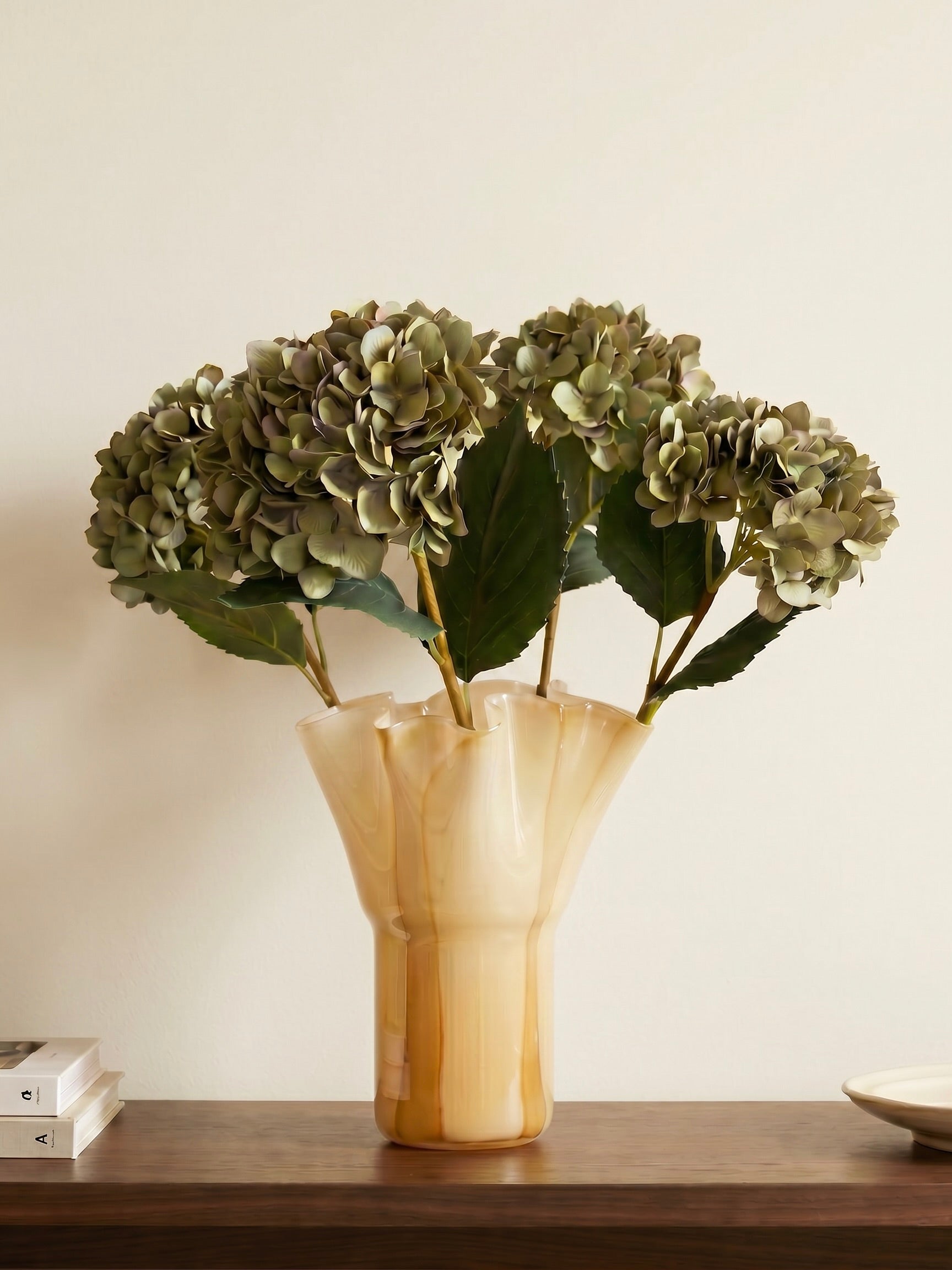 Decorative vase with green flowers on a wooden surface against a plain background