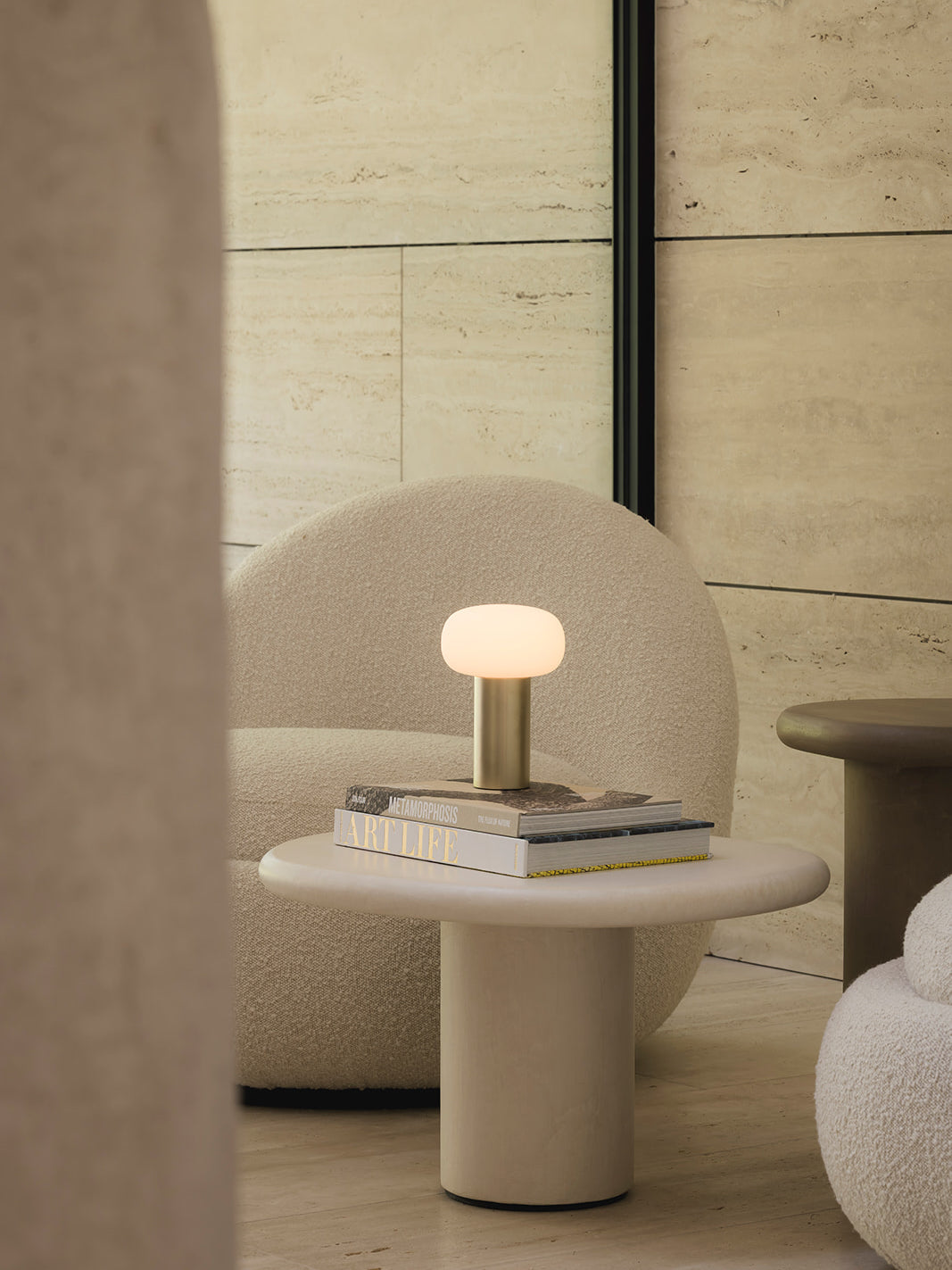 Elba cordless rechargeable table lamp in brushed gold creating soft ambient lighting on coffee table in luxury neutral interior with textured wall