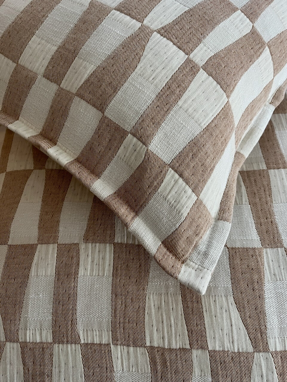 Close-up detail of caramel pattern cushion cover with neutral checkered woven fabric texture in soft beige and cream tones